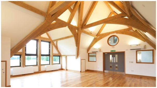View across the Aldenham School rehearsal room with exposed raw green oak beam and roof truss features