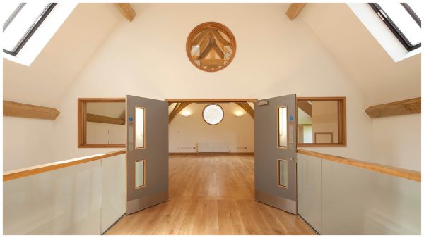 Internal view of access towards the gathering space via glass balustrade bridge which is flooded with natural light