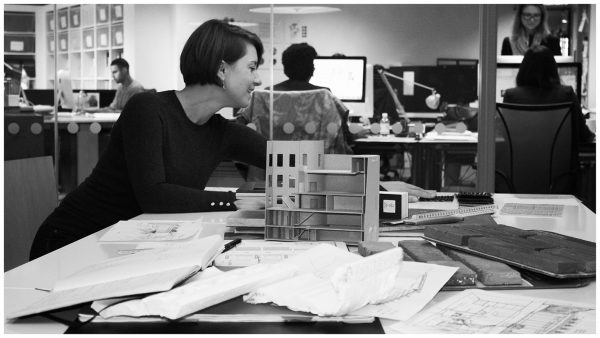 A female designer reaching for a fabric sample, amidst sketches, product samples and building models