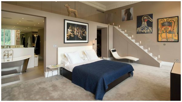 Double-height master bedroom with mezzanine walkway above ensuite bathroom room with free standing roll-top bath and dressing room