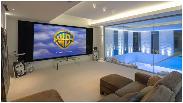 Lower ground floor home cinema room with coffered ceiling and view into adjacent swim spa