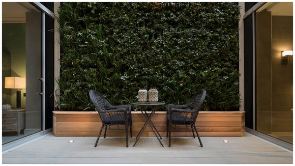 Sitting within the base of the courtyard is an millboard decked outdoor seating area, adjacent to a green living wall and timber clad planting box.