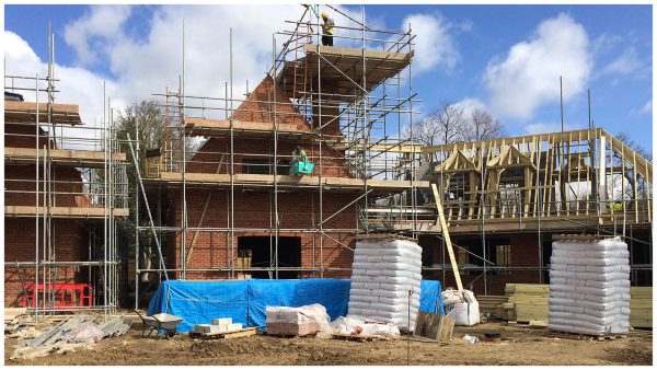 Scaffolding surrounds the structures of new residential homes as the brick façade is erected. Another property is in the timber frame construction stage.